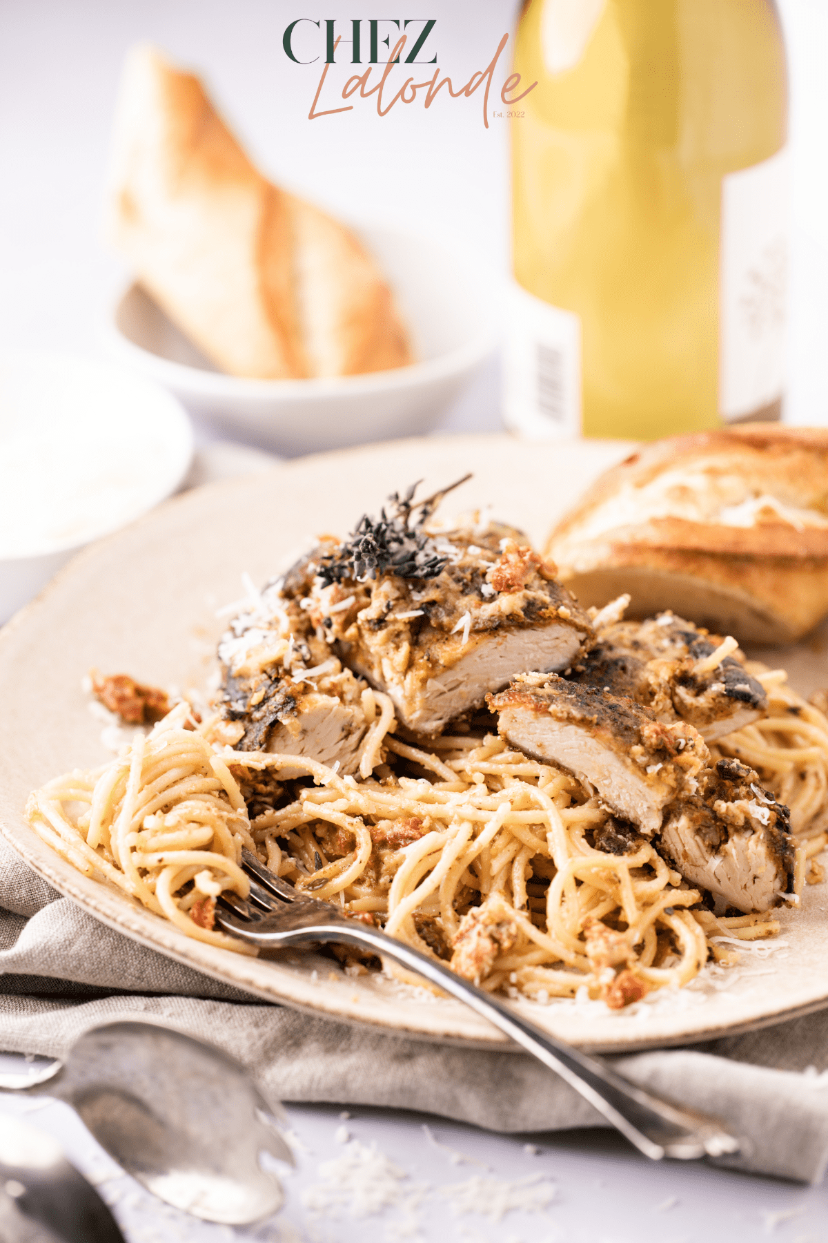 Cut out chicken breasts sitting on a bed of spaghetti with creamy sun-dried tomato sauce 