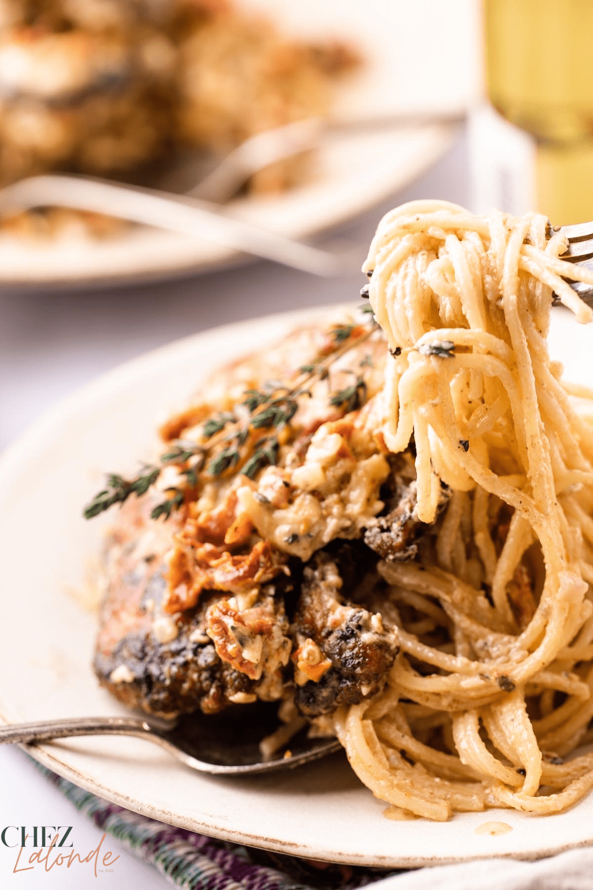 creamy Sun-dried tomato chicken pasta.  A fork is lifting up some spaghetti 