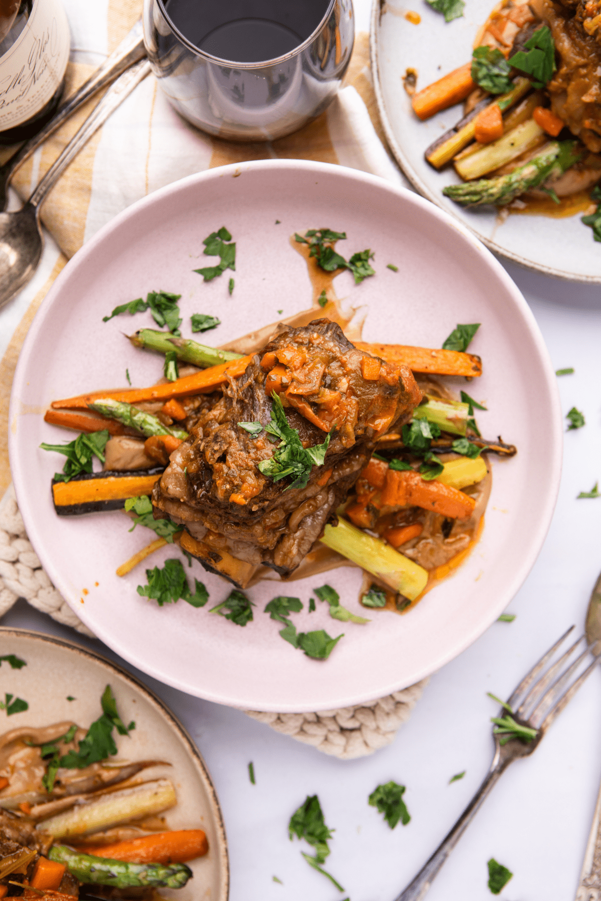 Braised beef short ribs with color carrots on round pink dish. 