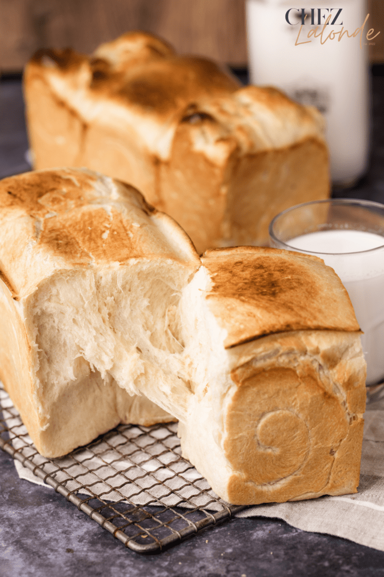 separating Japanese Milk bread. A glass on milk in behind the bread.