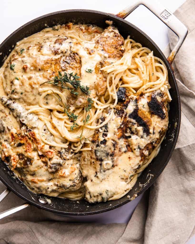 Chicken breasts with creamy sun dried tomato sauce pasta in a black frying pan