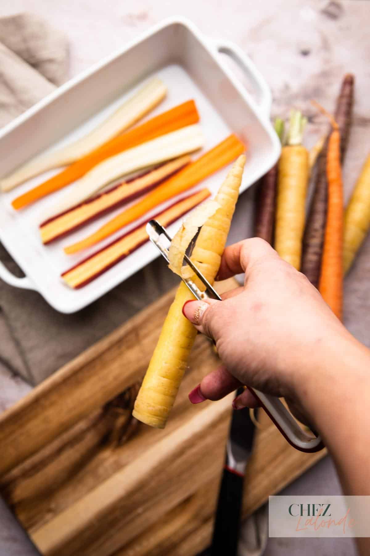 Peeling yellow color rainbow carrots over a small cutting board. 