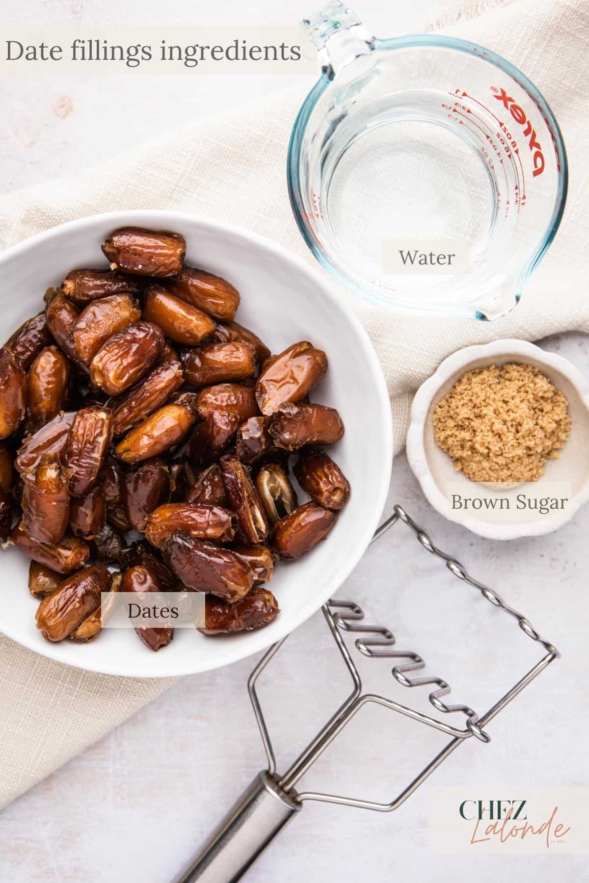 A bowl of dates next to a measuring cup, potato mashers and a bowl of brown sugar.