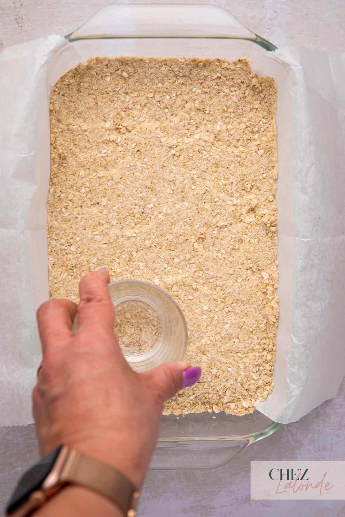 A person holding a glass and press oatmeal in it.