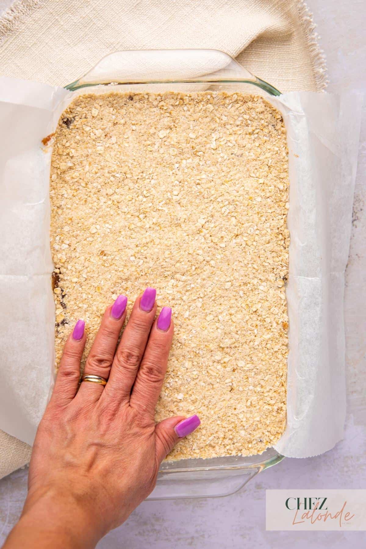 A hand is pressing down oatmeal toppings.