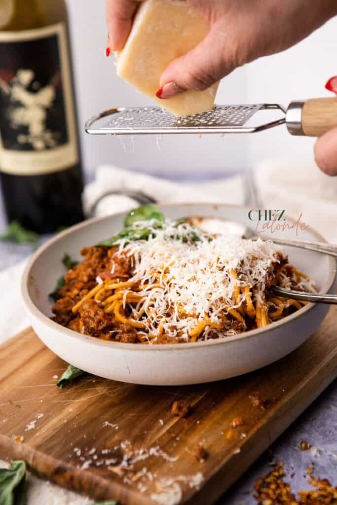 Spaghetti with meat sauce is topped with grated cheese. 