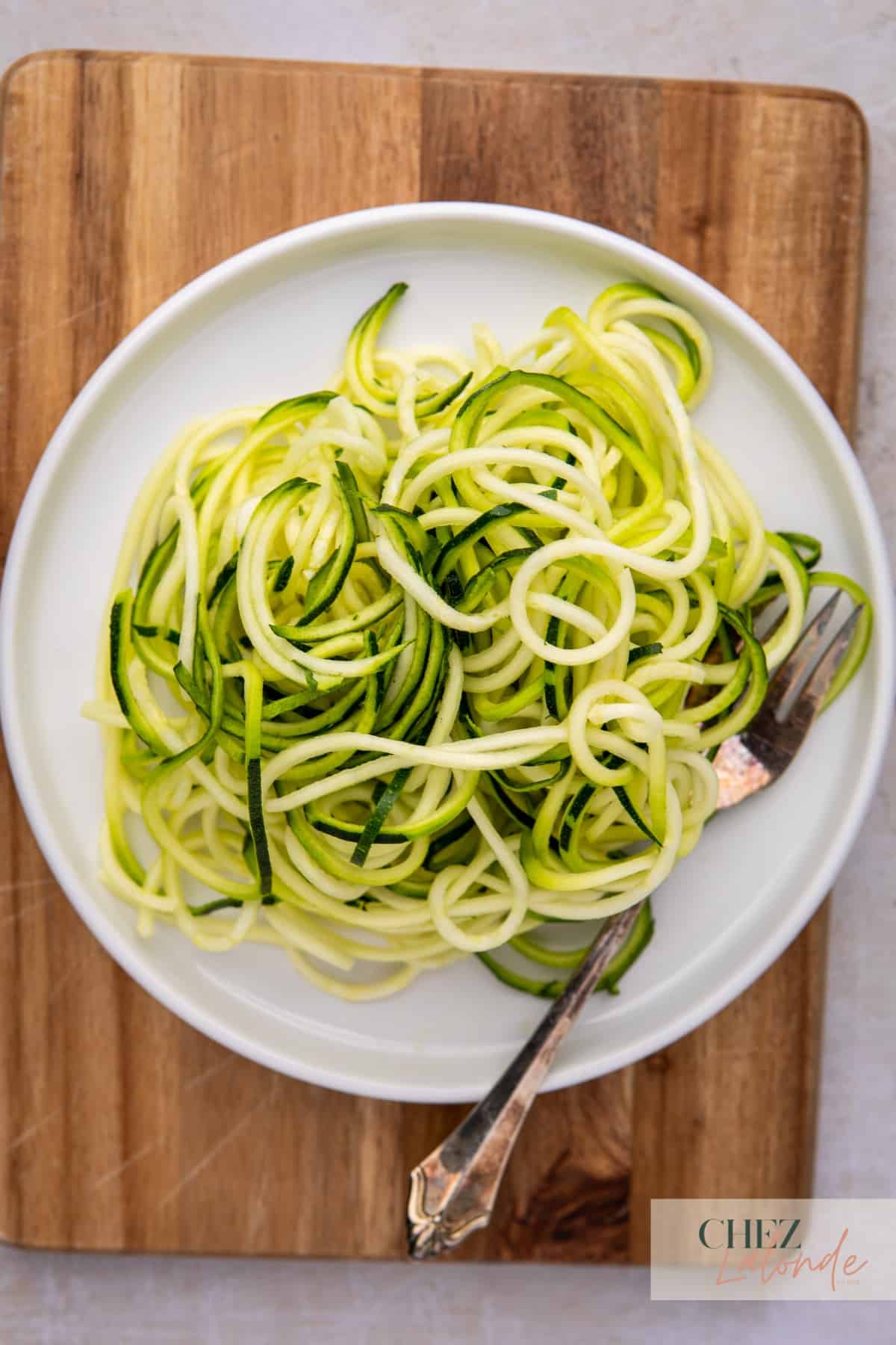 Zucchini noodles - Zoodles on a white round plate with a fork.  