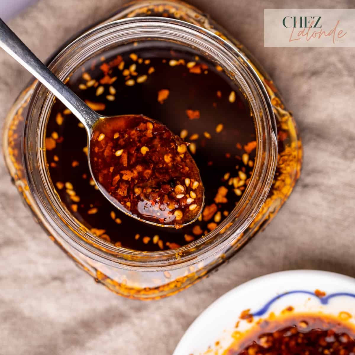 A spoon and a Mason jar full of Chinese chili Oil.