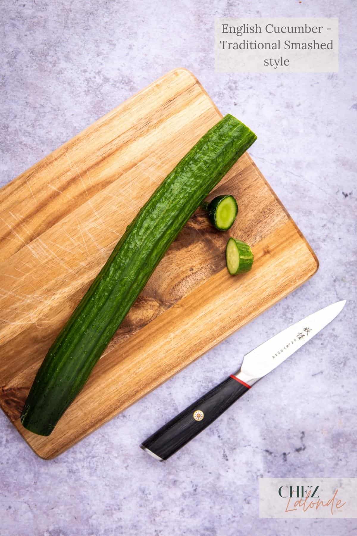 A English cucumber laying on top of a cutting board with a paring knife next to it. 