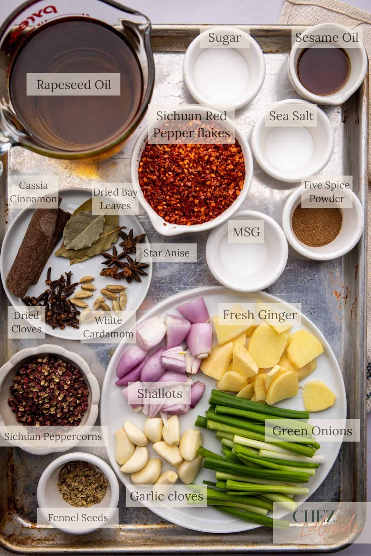 All ingredients needed for making Homemade chinese Chili Oil.  You will need Rapeseed oil, Green onion, ginger, garlic, shallot, cassia cinnamon, Sichuan Peppercorn, Bay leaves, star anise, dried cloves, white cardamom, fennel seeds, sichuan red pepper flakes, sugar, sea salt, toasted sesame oil, five spice powder, and MSG. 