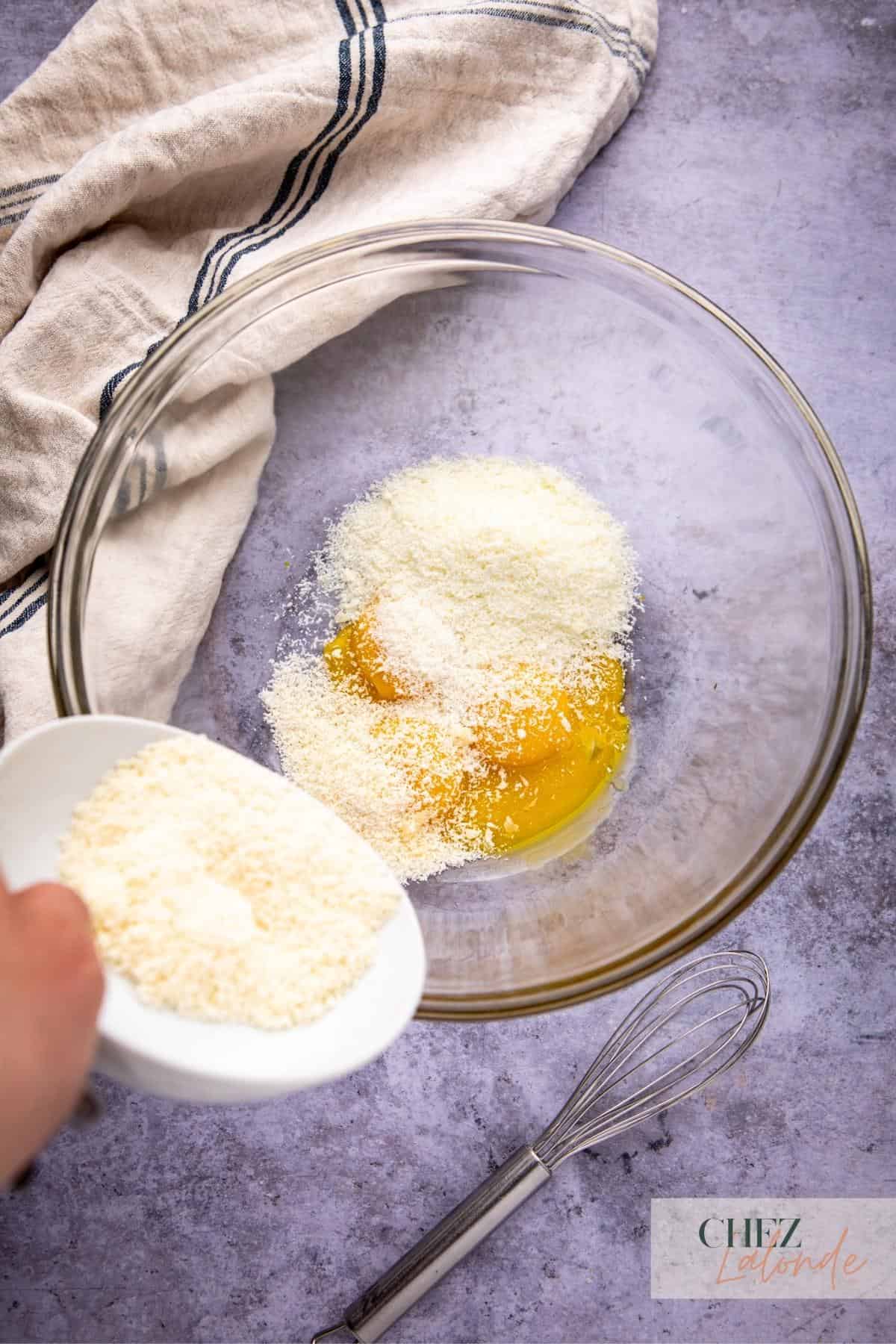 Mixing egg yolks and grated cheese in a clean bowl. 
