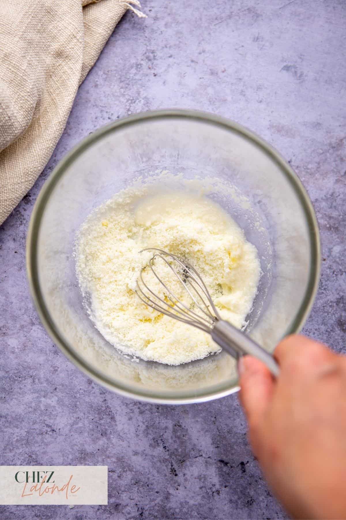 Mix pasta water and grated pecorino cheese in a glass bowl with a whisk.