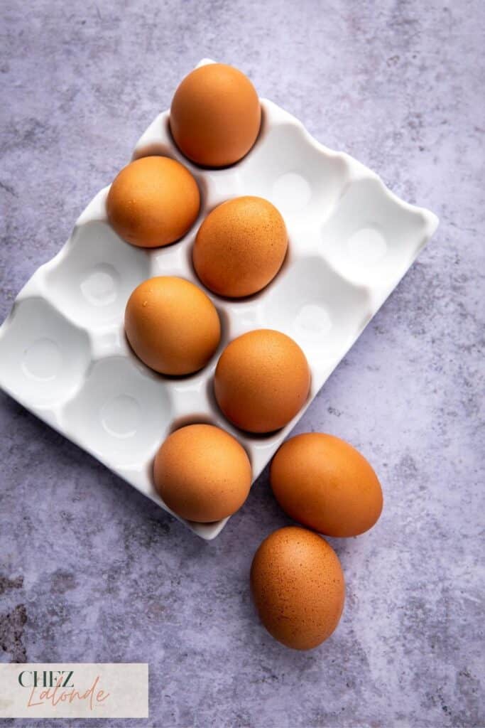 8 raw eggs on a porcelain egg tray.  