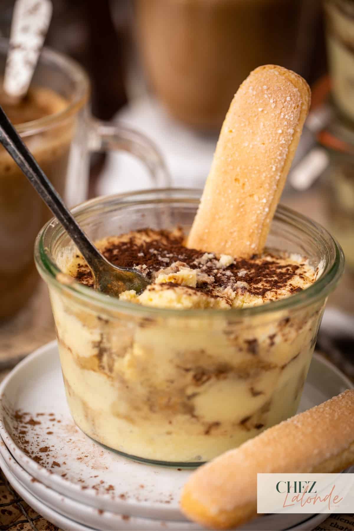 Italian style Tiramisu in a jar that is decorated with a ladyfinger. 