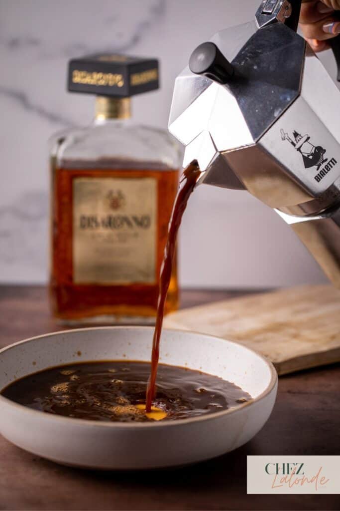 Pouring coffee on a big plate with a bottle of Amaretto in the background. 