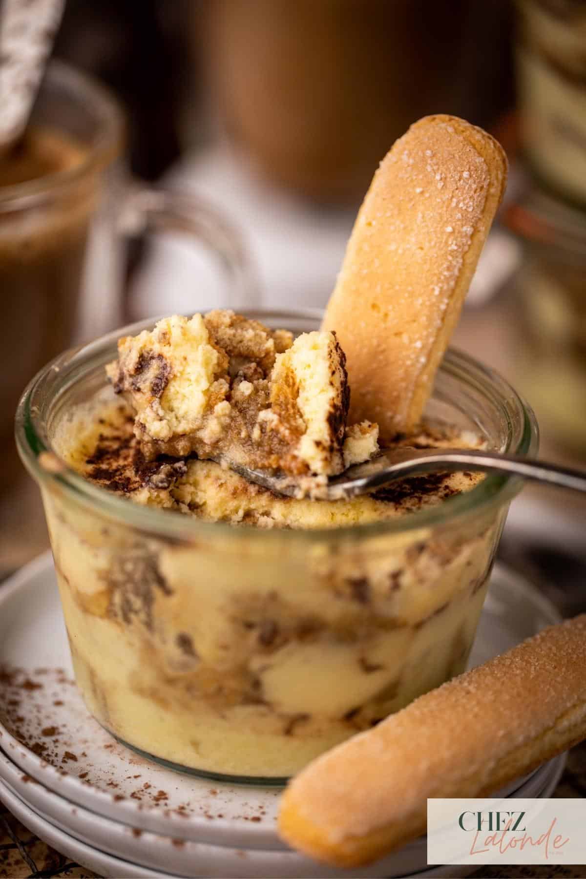 A fork is digging in the jar and scooped up some Tiramisu. 