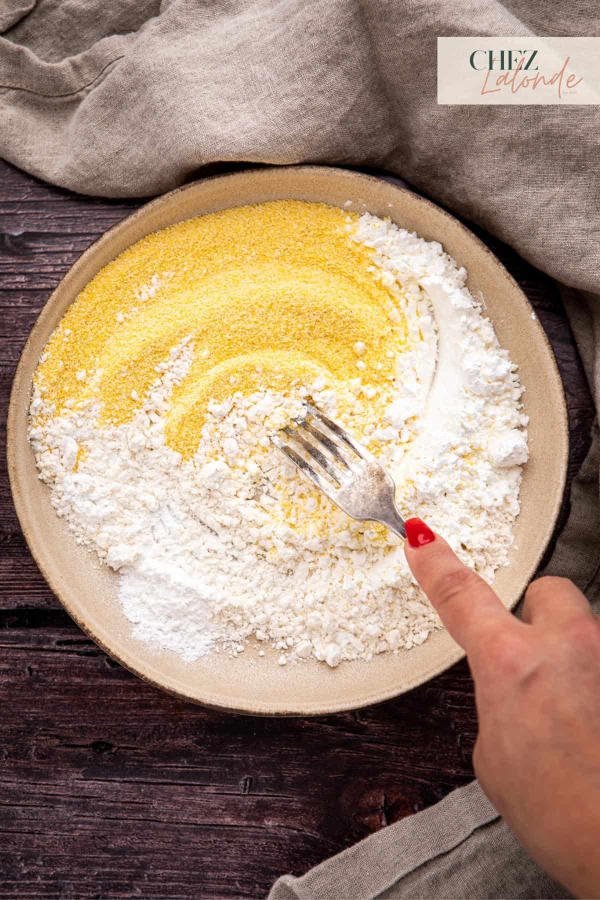 Using a fork to mix cornmeal, all purpose flour, cornstarch, and baking powder. 