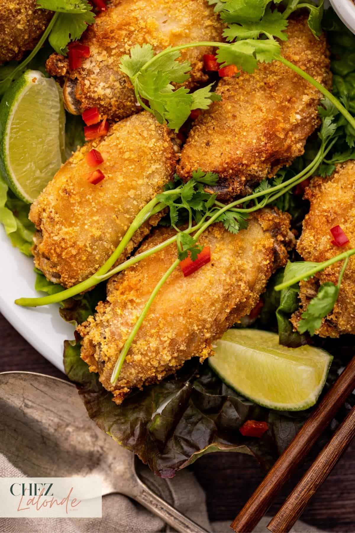 Air Fryer Chicken wings that are garnished with lime wedges, Fresno pepper, and cilantro. 