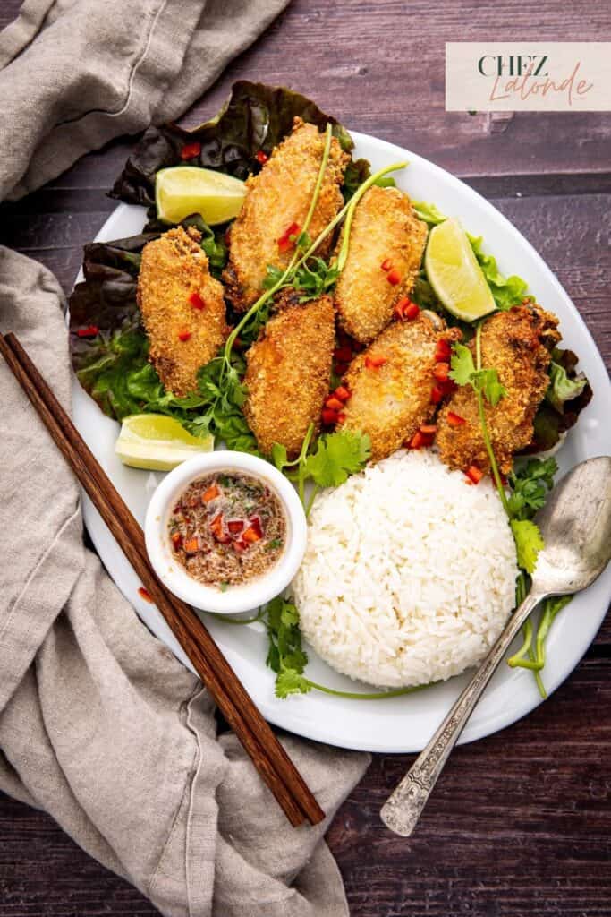 Air Fryer Chicken Wings on the bed of lettuce with special Vietnamese dipping sauce. Served with white rice and garnished with fresh lime wedges, cilantro, and diced fresno chili pepper.