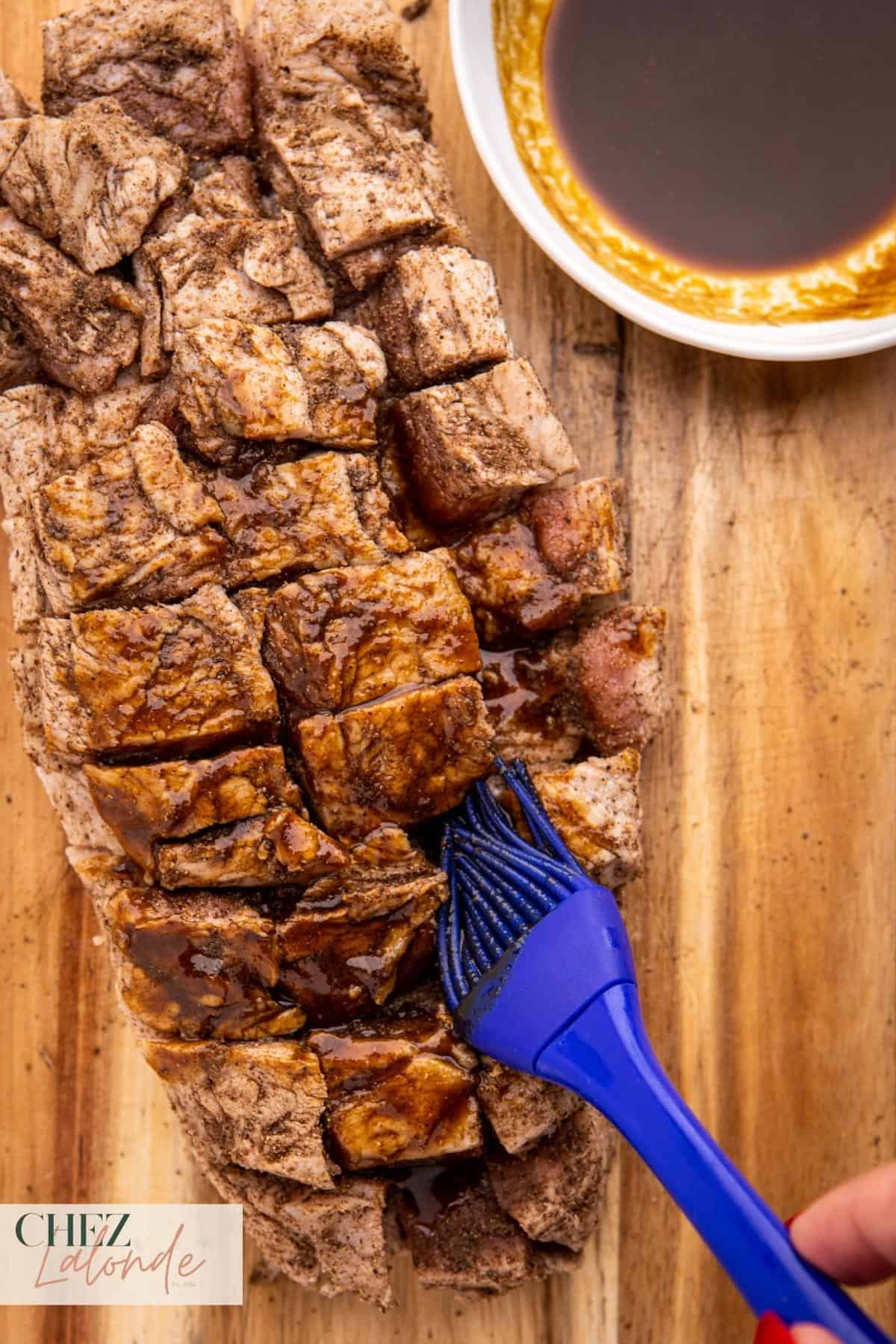 using a silicon brush to brush wet seasoning on the meat.