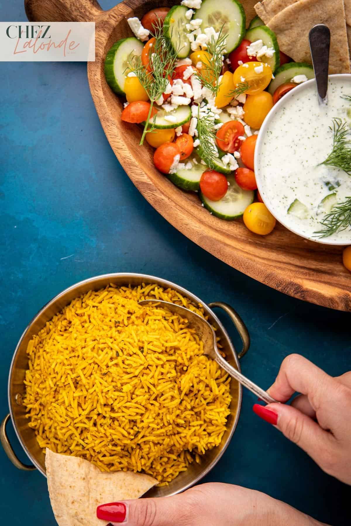 A bowl of Mediterranean yellow rice with Tzatziki sauce and Greek Salad. 