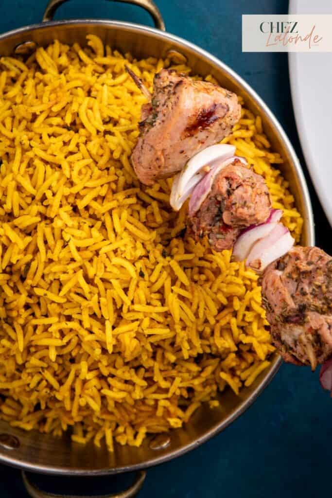 A close up photo of Mediterranean yellow rice with a Sous Vide Pork Tenderloin Souvlaki skewer.