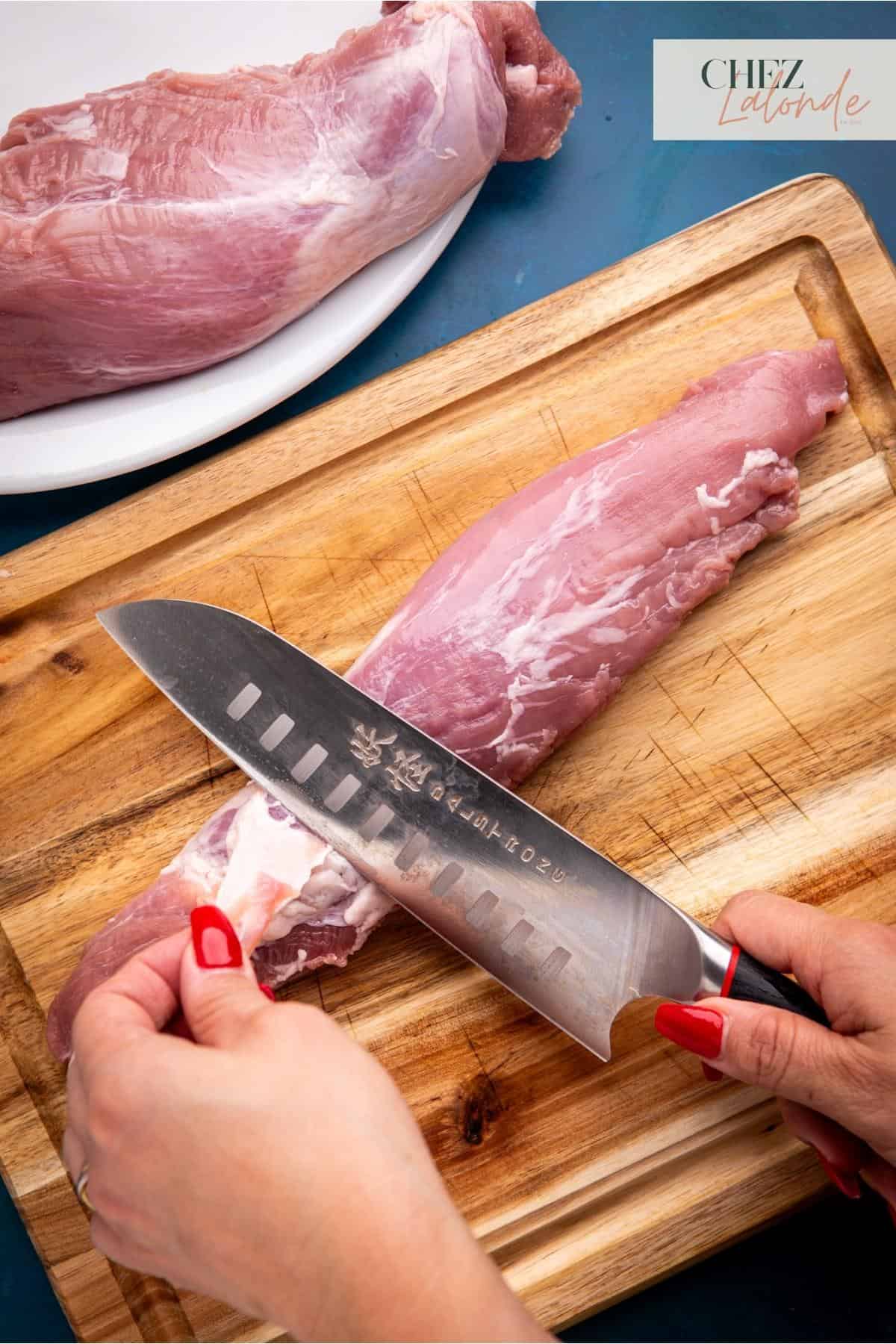 Using a knife to carefully trim off the silver lining on the tenderloin.