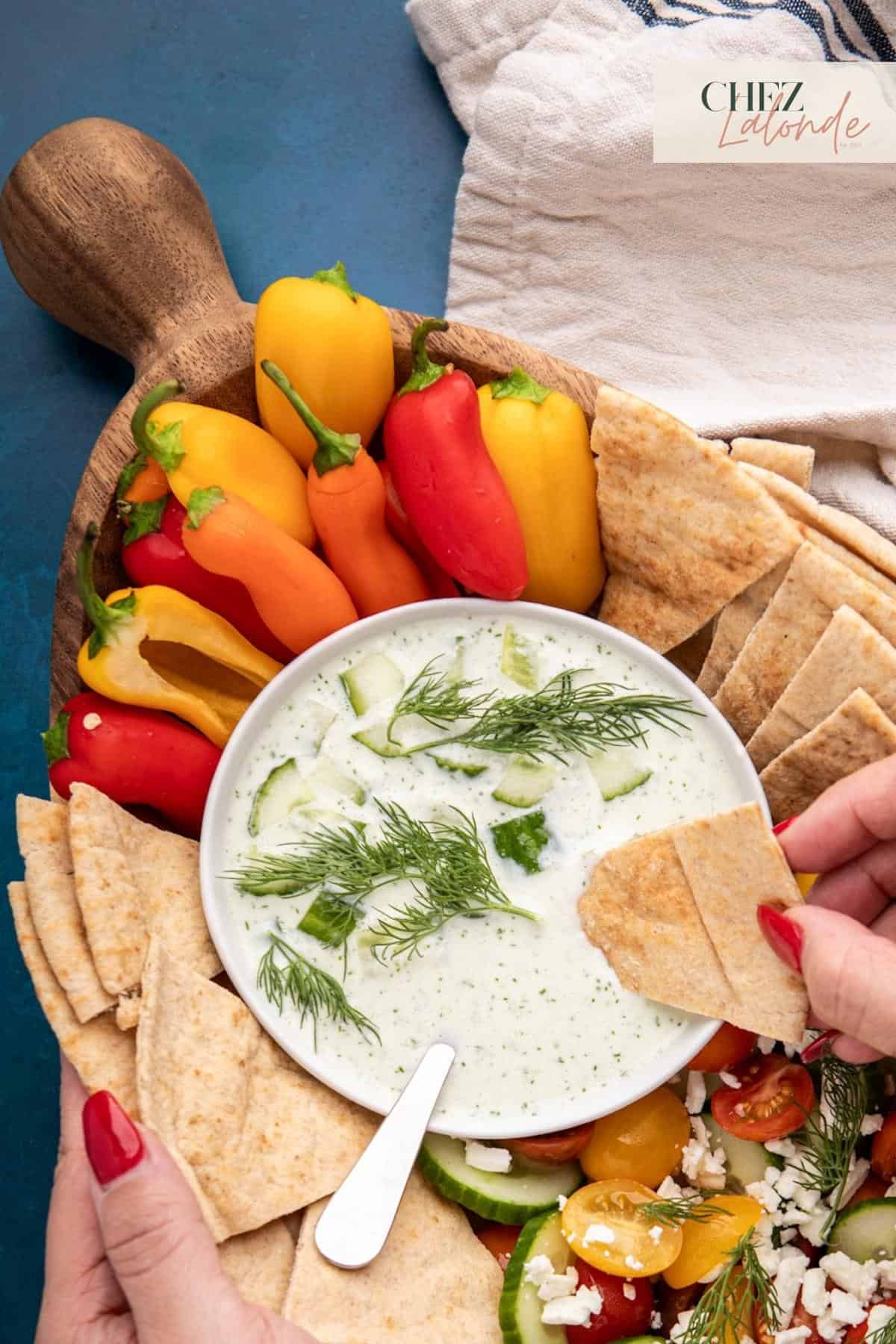 A bowl of tangy Tzatziki sauce with Pita bread and fresh peppers. Garnished with Dill and cucumbers.