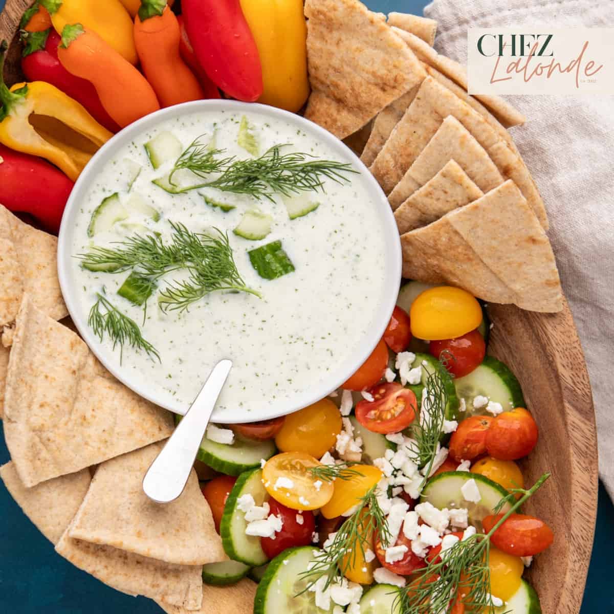 A bowl of Greek Tzatziki sauce with assortment of fresh vegetable and pita bread.