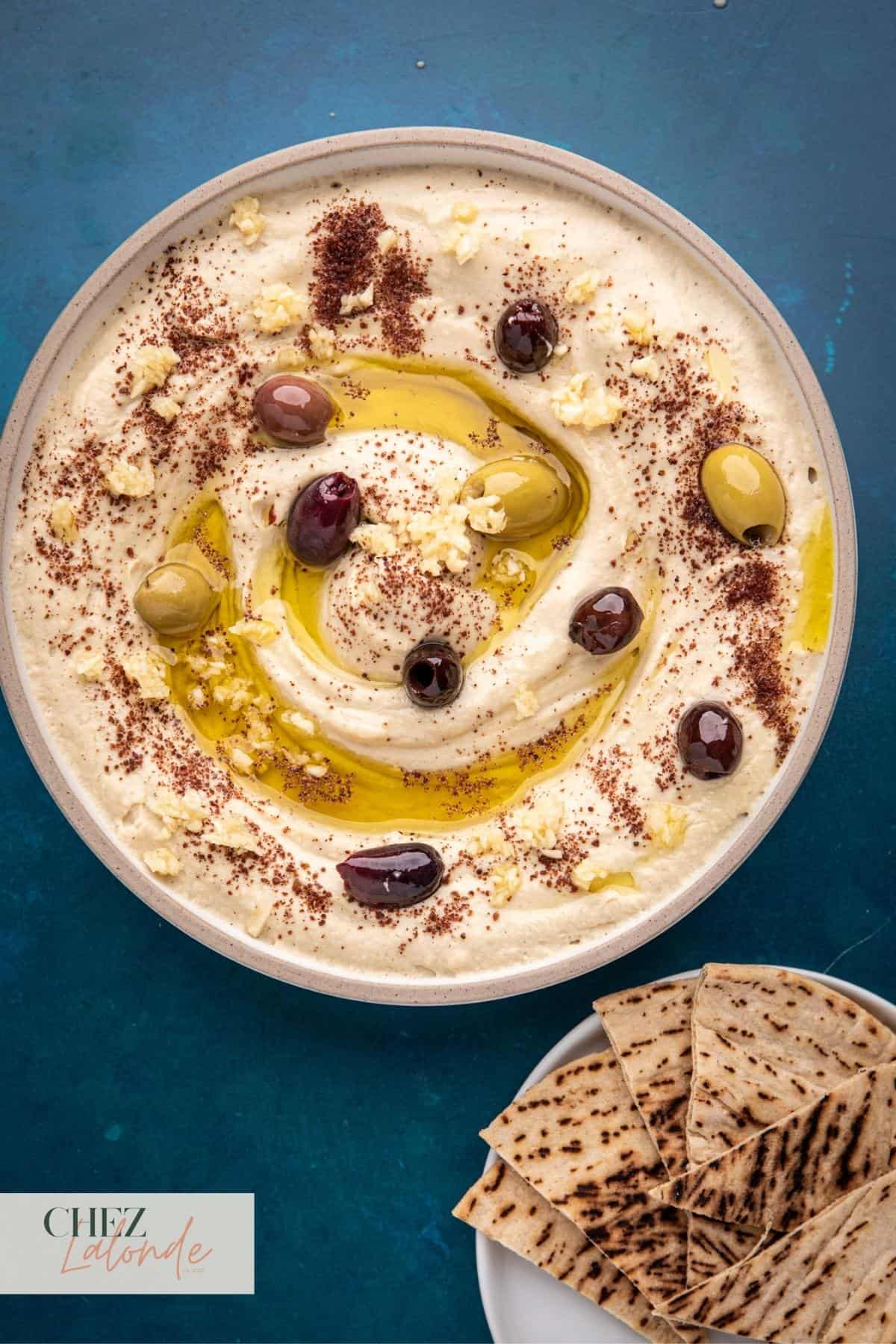 A bowl of hummus with slices of pita bread.