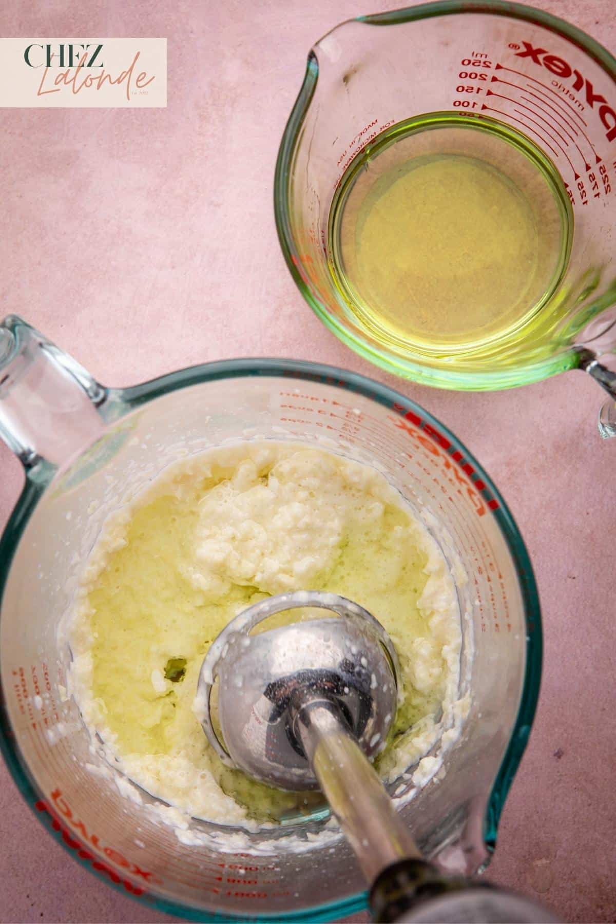 With the immersion blender running, slowly pour the grapeseed oil, little by little, into the mixture. 
