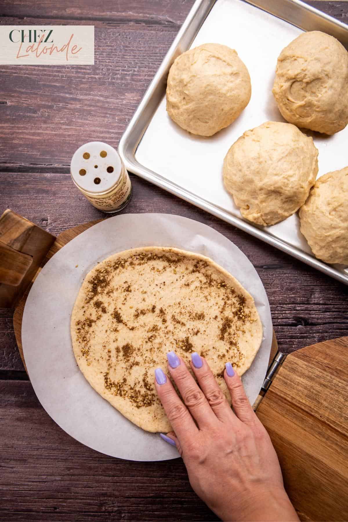 Using my hand to press down the Za'atar seasoning on the dough.