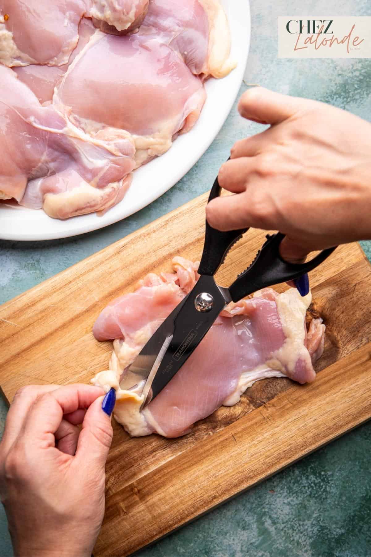 trimming fat and impurities from the chicken thighs with a pair of scissors. 