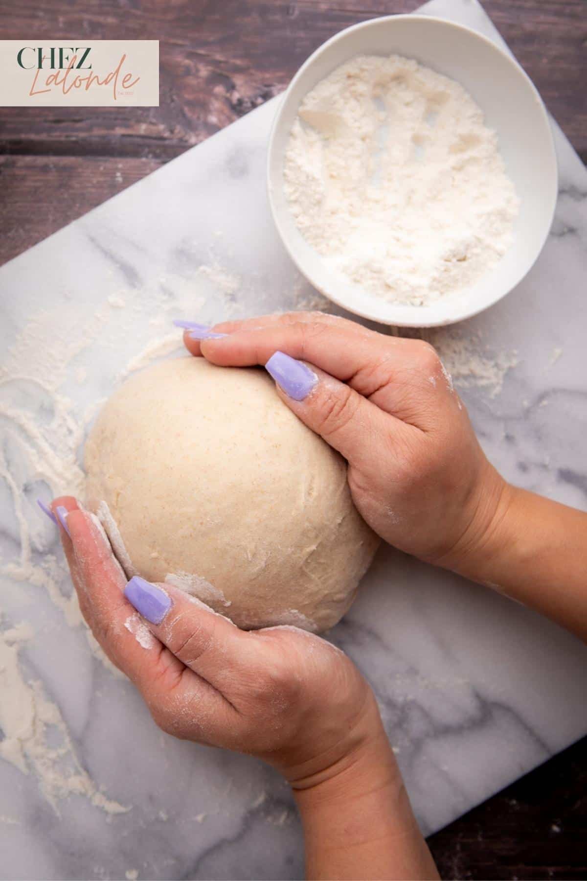 After kneading the dough in the stand mixer, transfer it to a floured kitchen counter and shape it into a ball by hand.