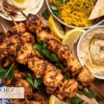 Many skewers of Air Fryer Shish Tawook on an Mezze Platter. Served with Hummus, Baba Ganoush, and yellow rice.
