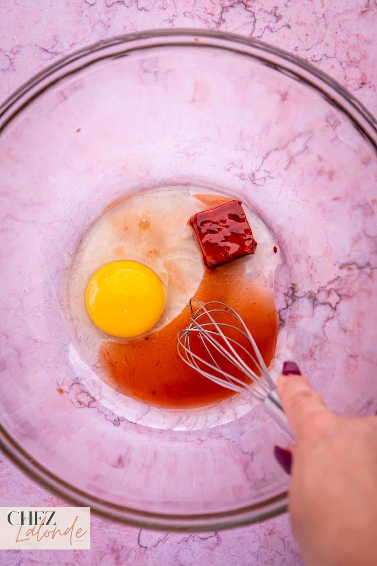 In a large bowl, whisk a large egg, combining it with a piece of fermented red bean curd and a tablespoon of red bean curd juice.