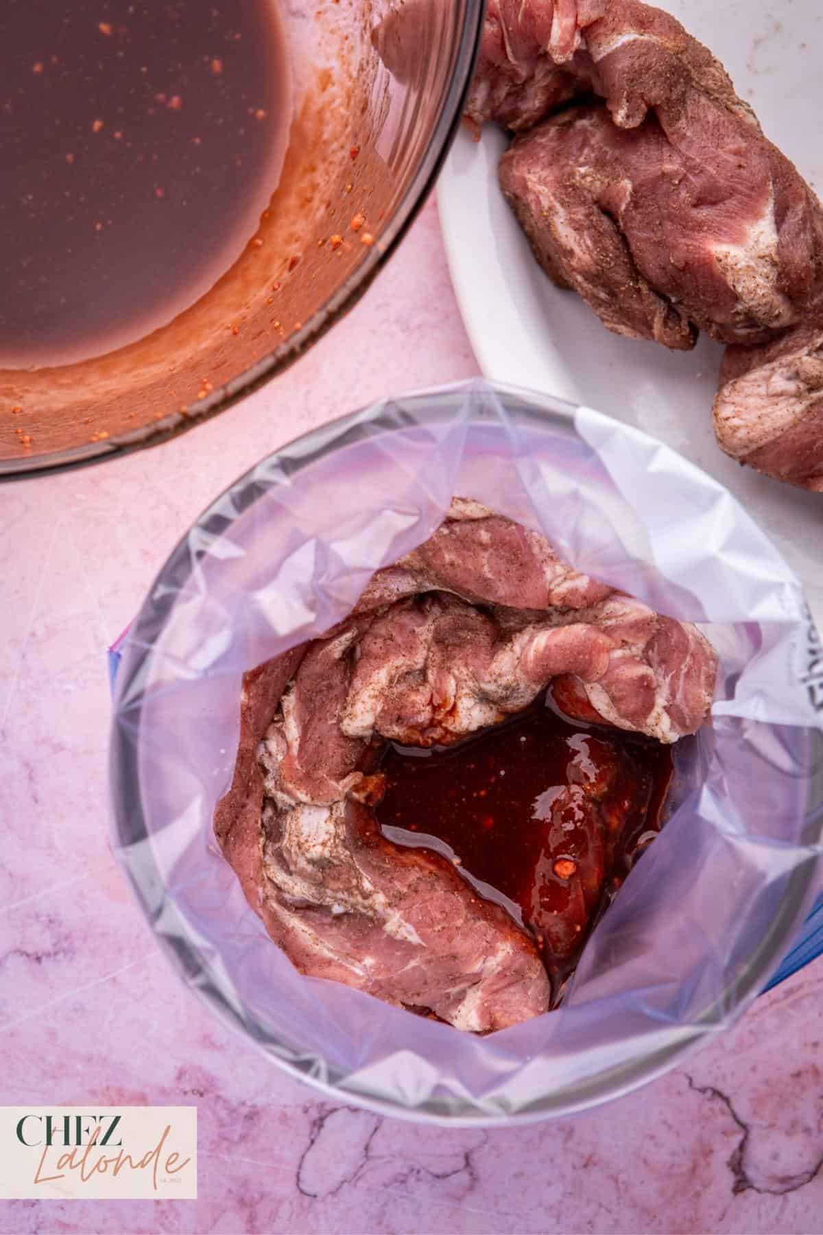 Position a freezer-grade Ziploc bag atop a slender bowl, carefully nestling the pork within the bag's confines. Proceed to pour the prepared Char Siu marinade into the bag. 