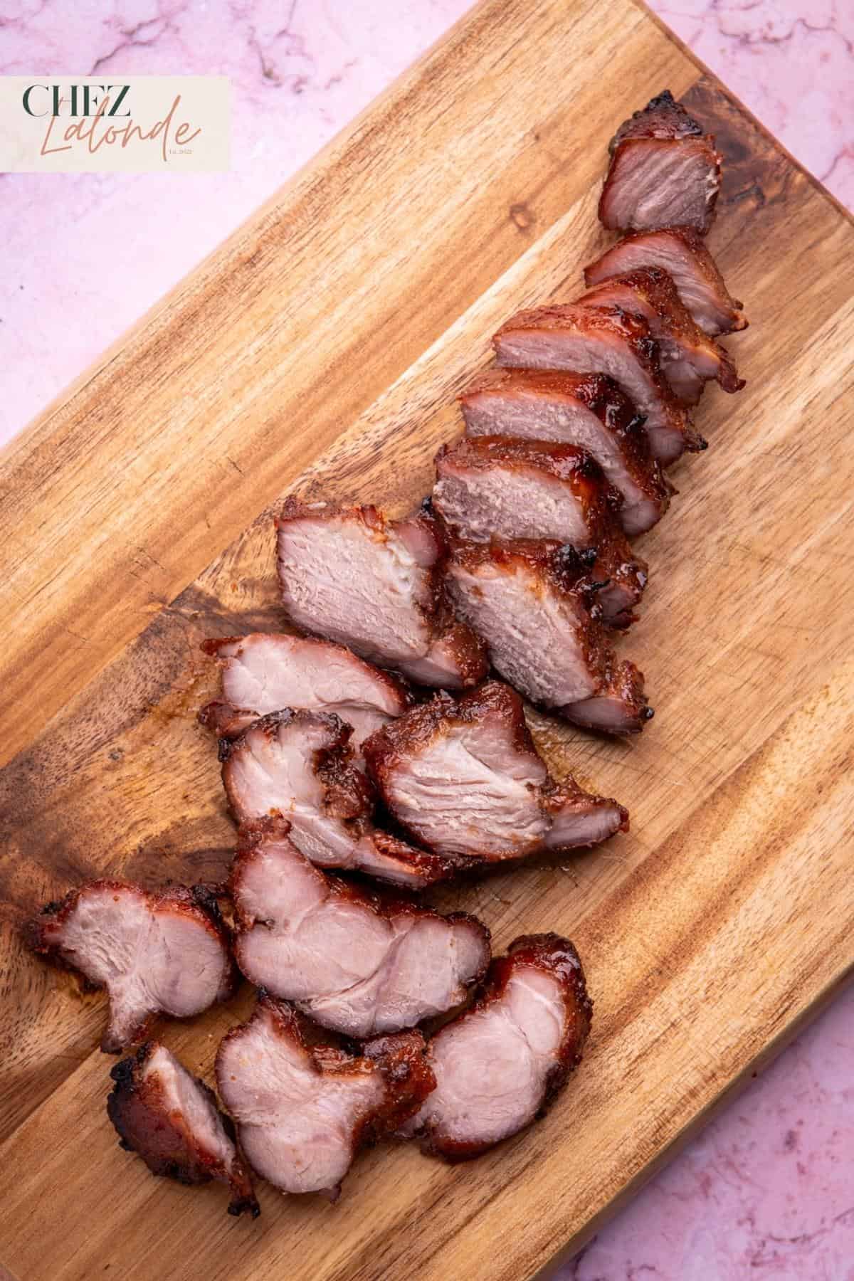 Many pieces of sliced Sous Vide Chinese BBQ pork on a cutting board. 