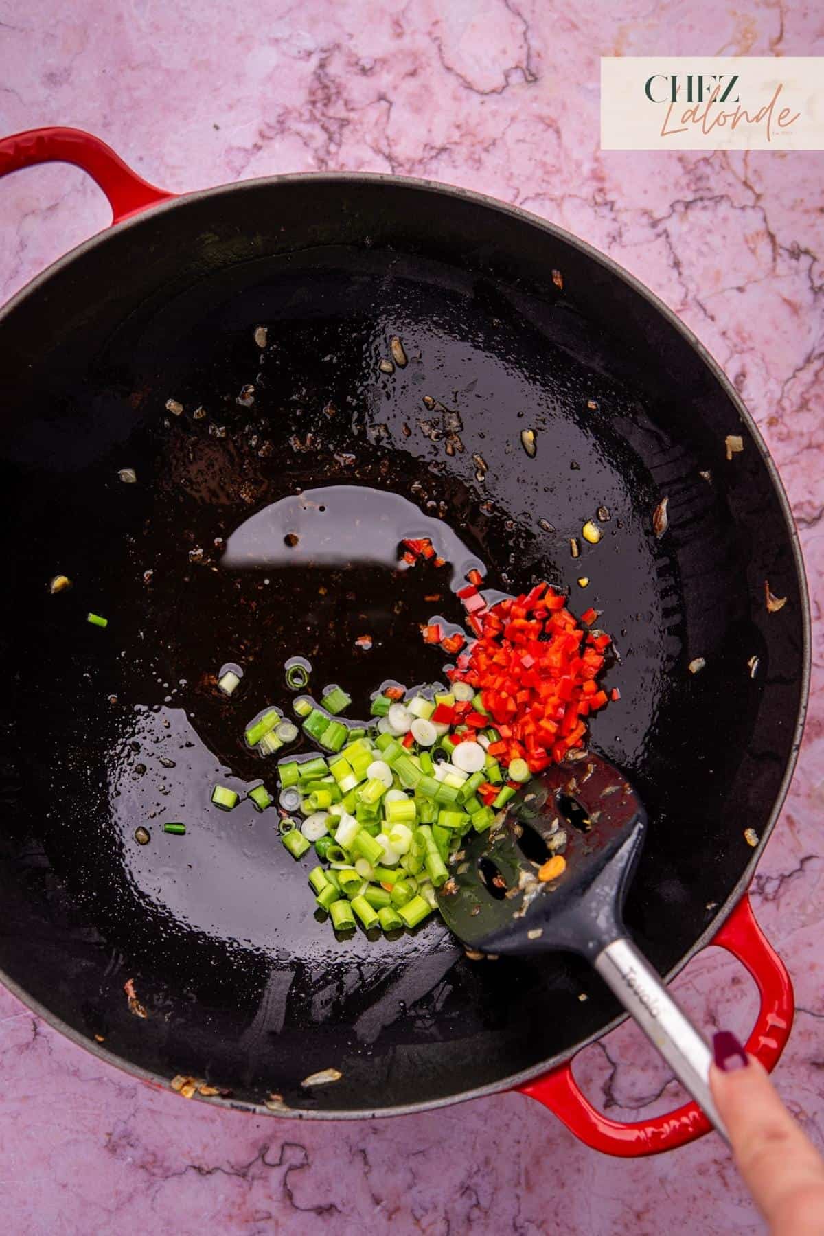 In the wok, add 4 tablespoons of avocado oil. Sauté chopped green onion and Fresno red pepper for 30 seconds or until fragrant. 