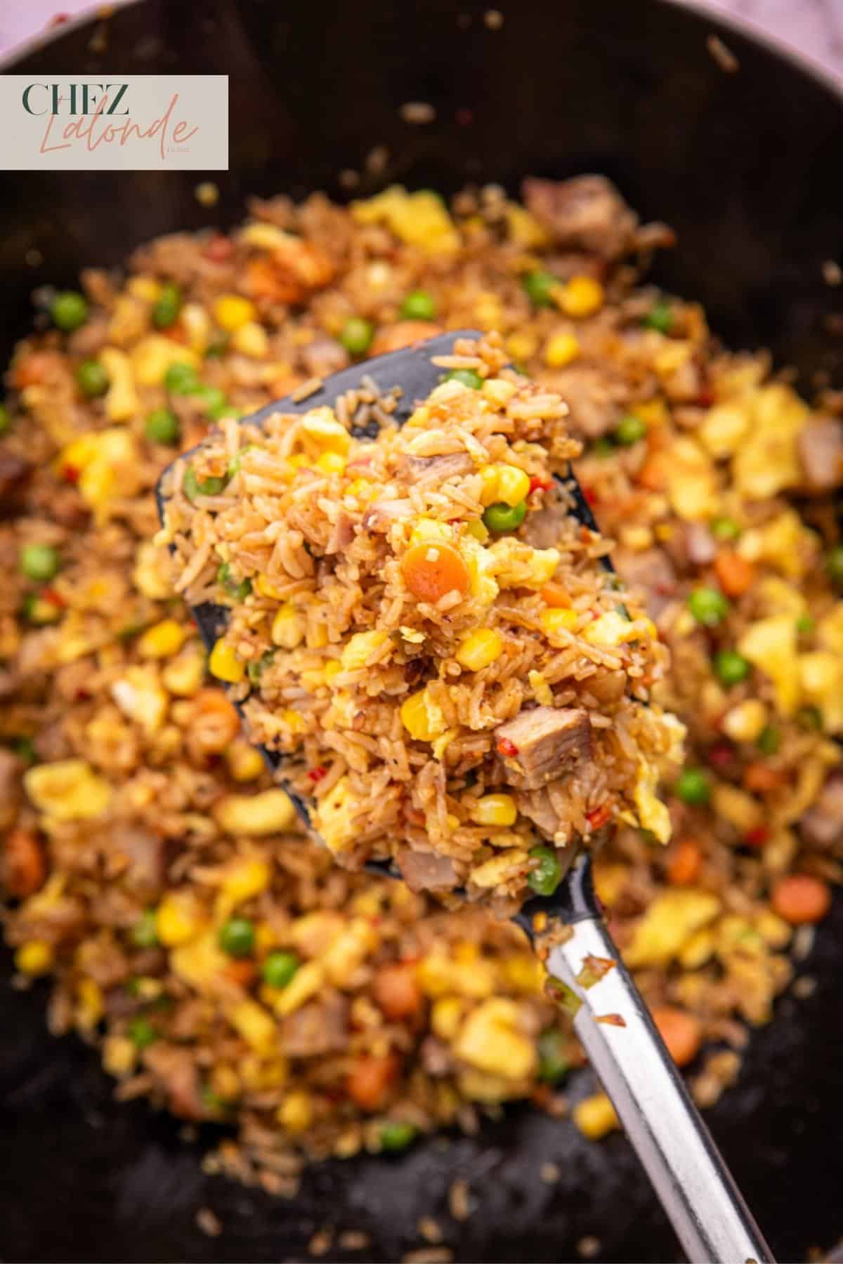 A spatula is scooping up some fried rice. 