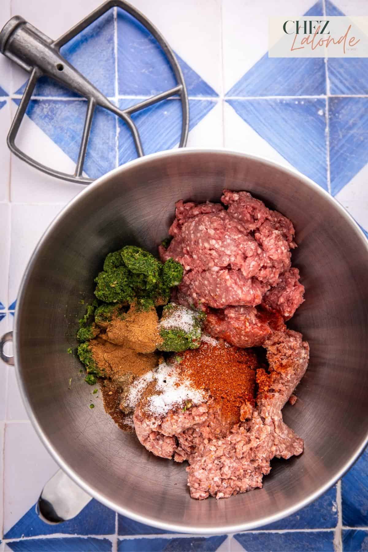 A mixing bowl fill with minced beef and lamb.  Also with vegetable mixtures and assortment of spices. 