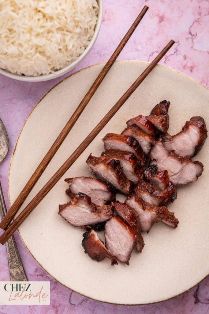A plate of sous vide Chinese BBQ pork served with a bowl of rice.